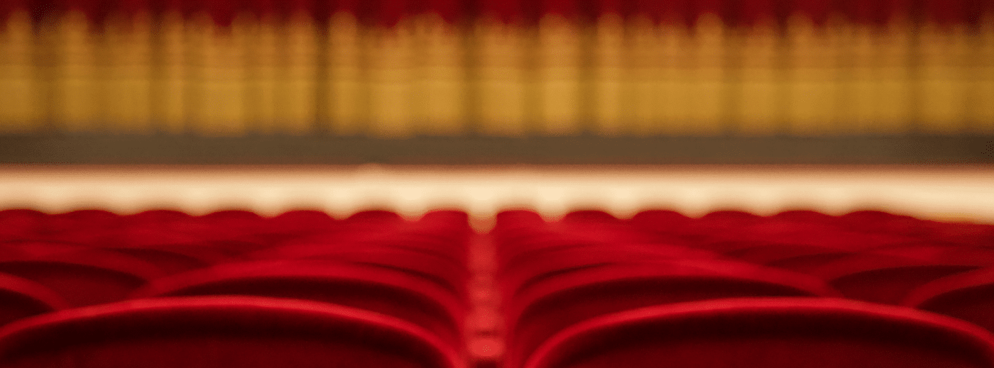 Red theatre chairs with a curtained stage in the background